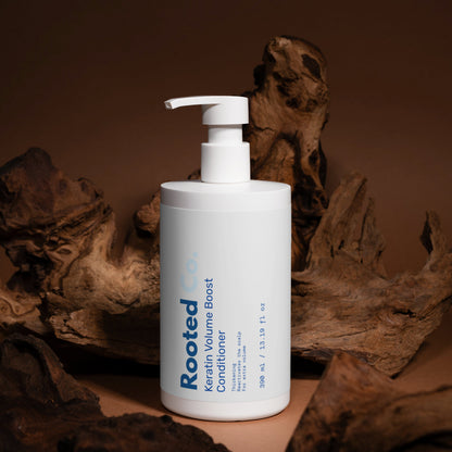 White bottle of 'Rooted' conditioner with pump on a brown background