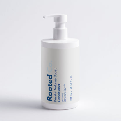 White bottle of 'Rooted' conditioner with pump on a light gray background