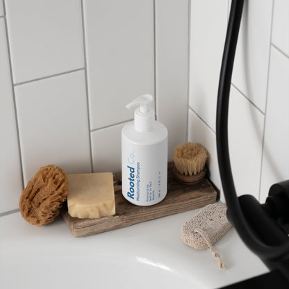 Bathroom counter with 'SAMI beauty' product, sponges, and soap on a wooden tray.