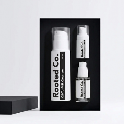 Three bottles of Rooted Co. skincare products in a black box on a white background