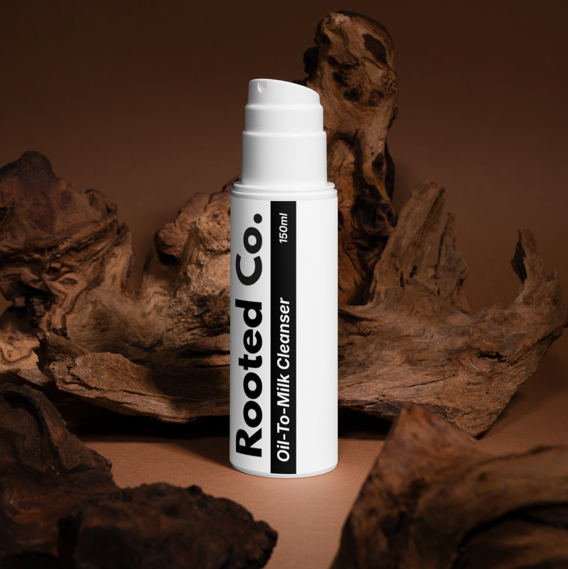 White bottle labeled 'Rooted Co.' on a brown background with natural elements.