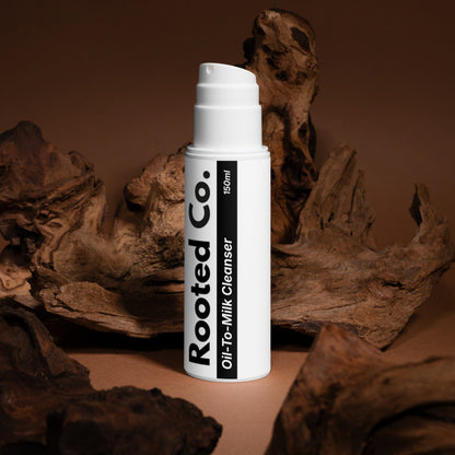 White bottle labeled 'Rooted Co.' on a brown background with natural elements.